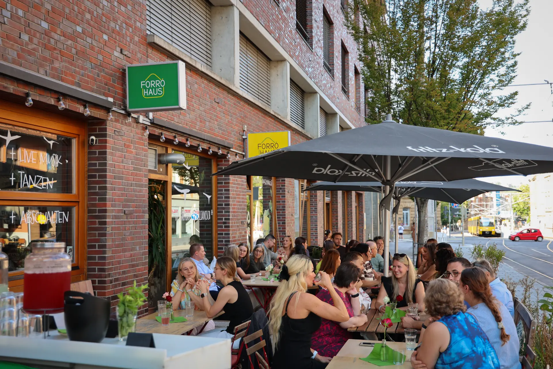 Die begrünte Terrasse mit Holztischen und Lichterketten